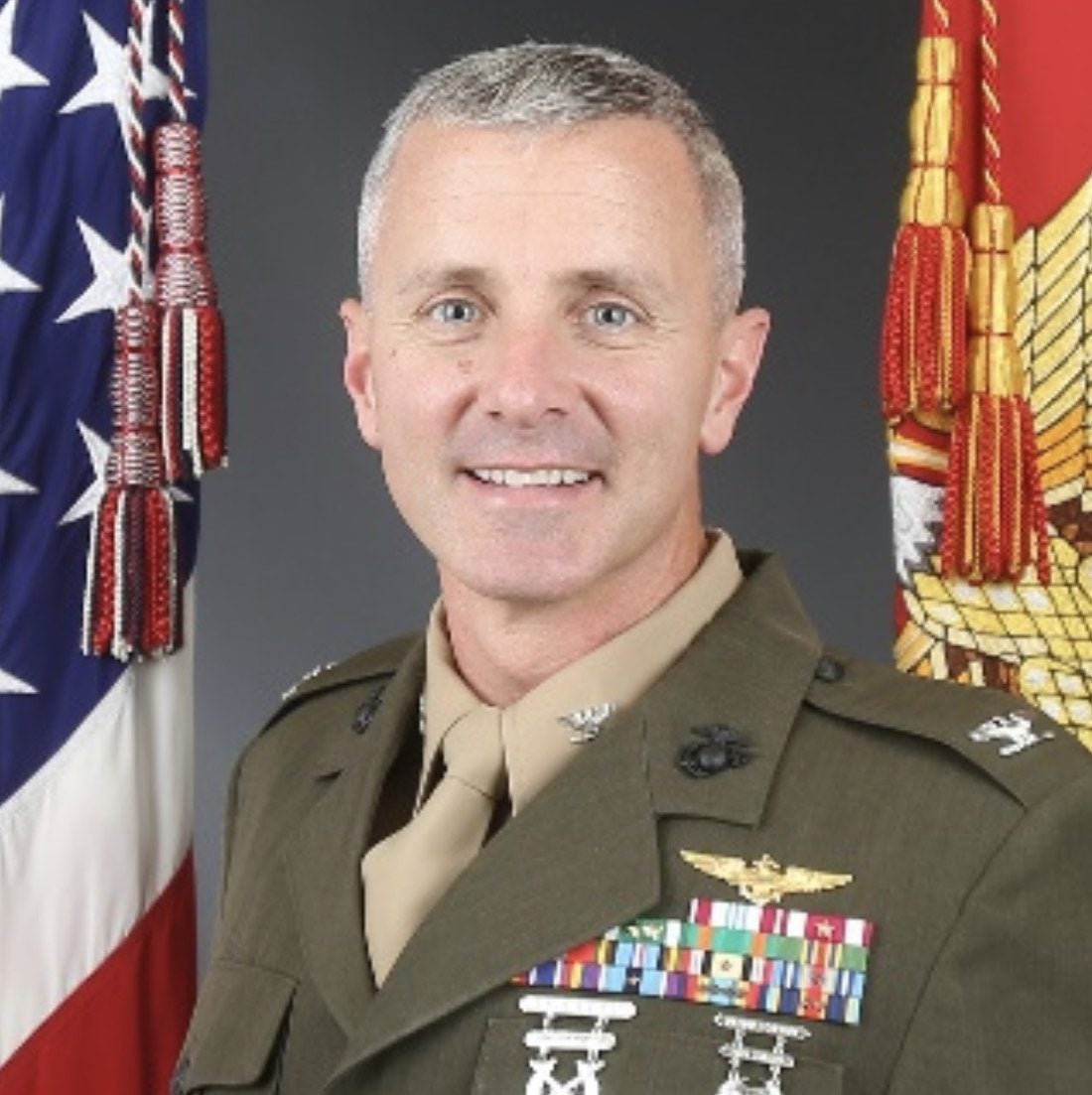 Col Vincent J Ciuccoli in military clothing standing in front of the US Flag