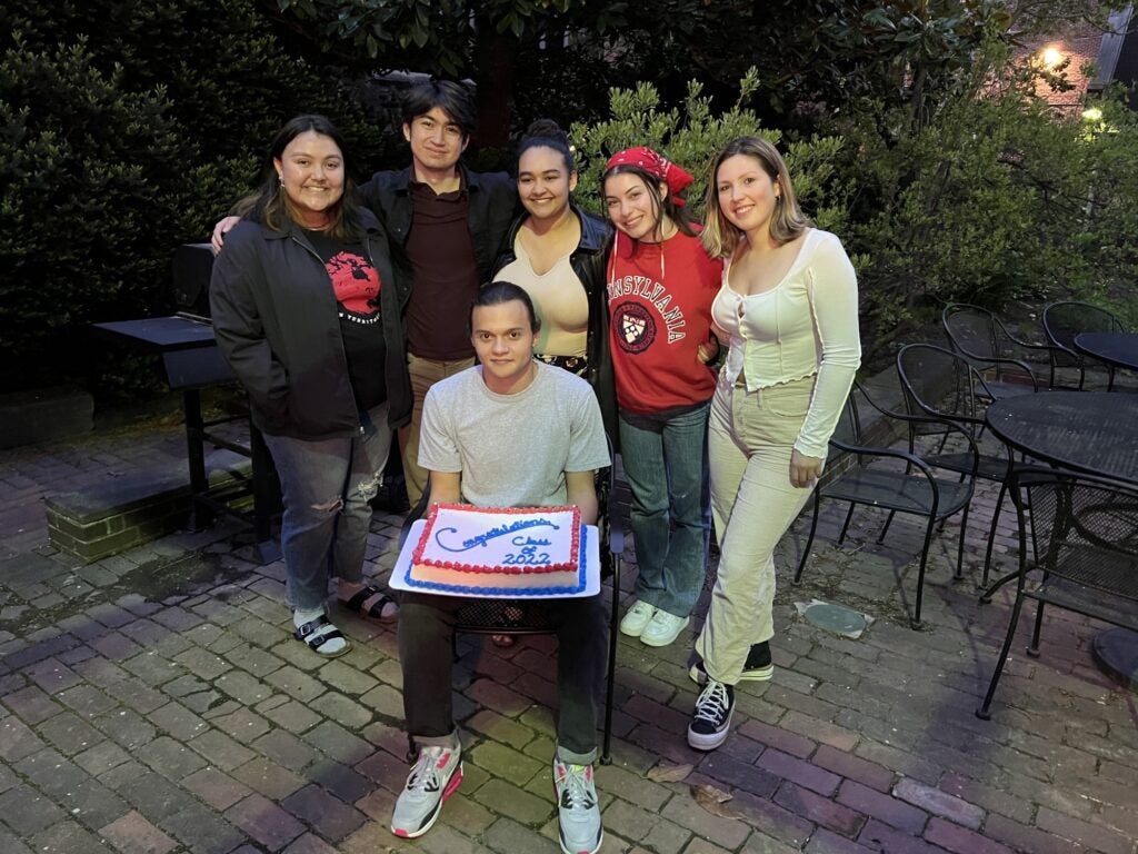 Students outdoors with a large celebration cake.