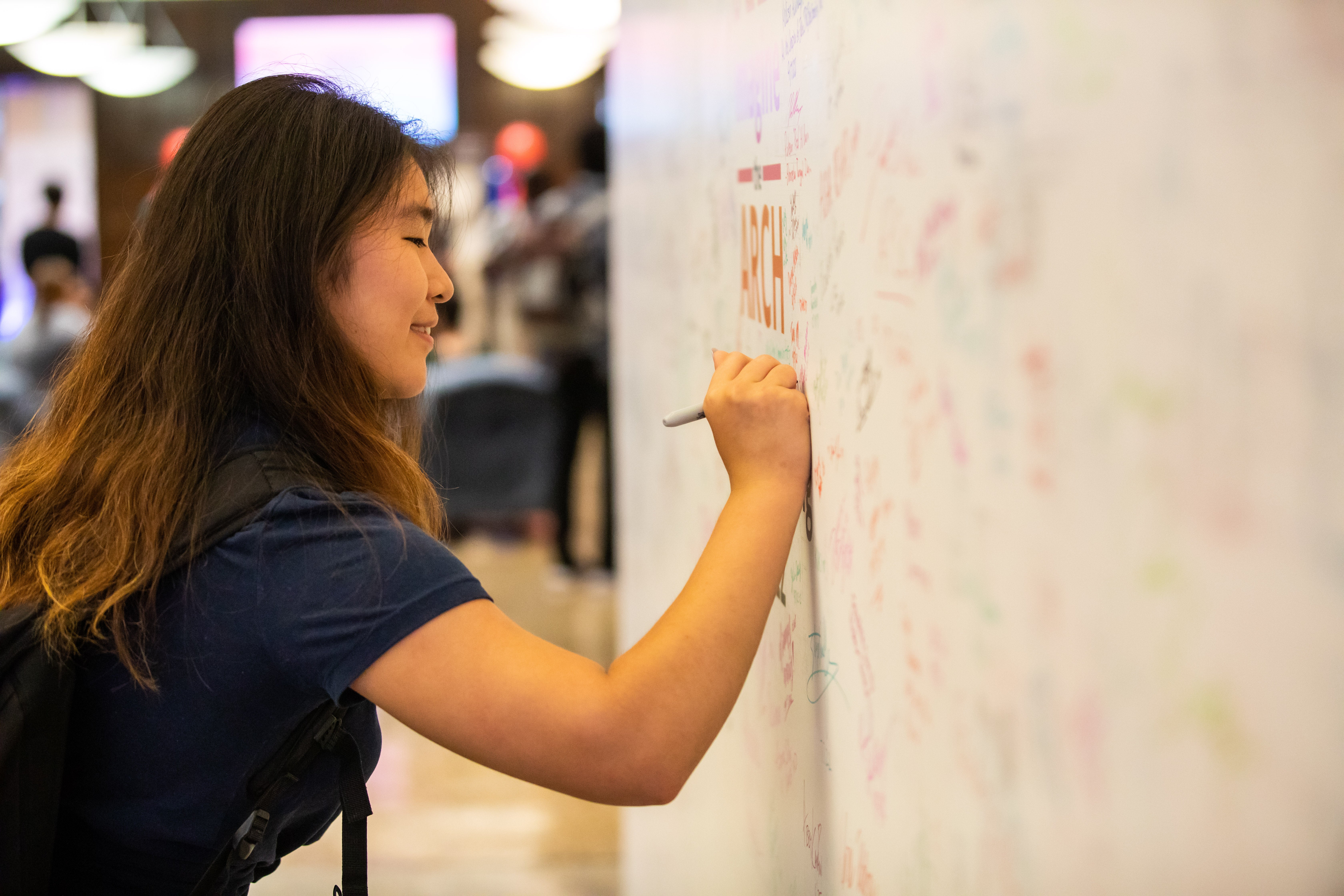 Penn student signs the ARCH Reimagine wall