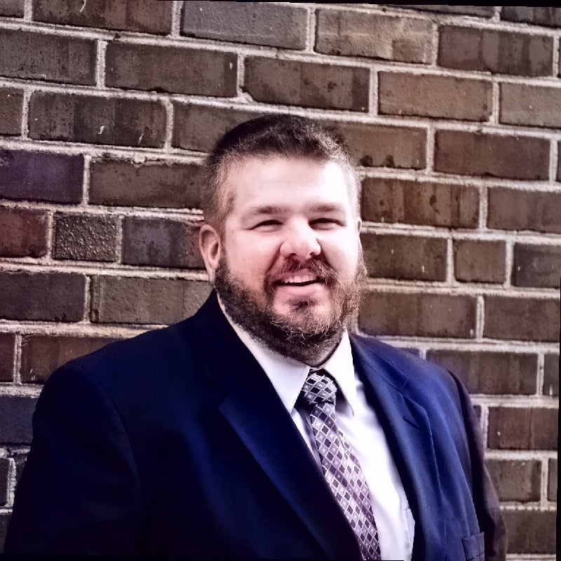 Rob Butler outdoors stands against a brick wall.