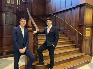Michael and Chris stand in front of a stairwell in Houston Hall