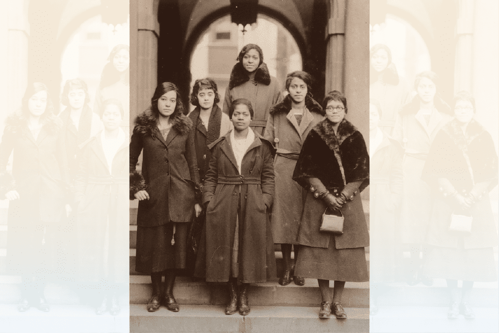 This sepia tone features a group of women wearing heavy coats and standing on steps.