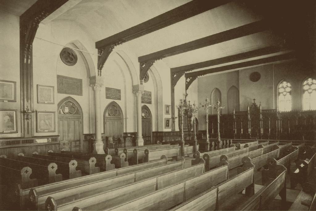 This sepia tone photo features a room filled with wooden pews.